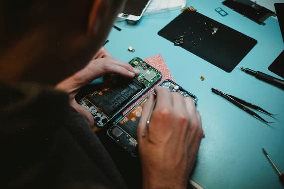 Technician repairing disassembled smartphones with tools on work table