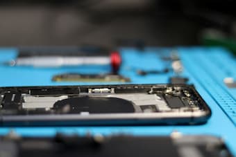Disassembled smartphone with components on blue repair stand