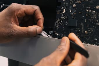 Hands with tools repairing a computer motherboard