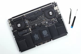Disassembled laptop with motherboard, battery and repair tools